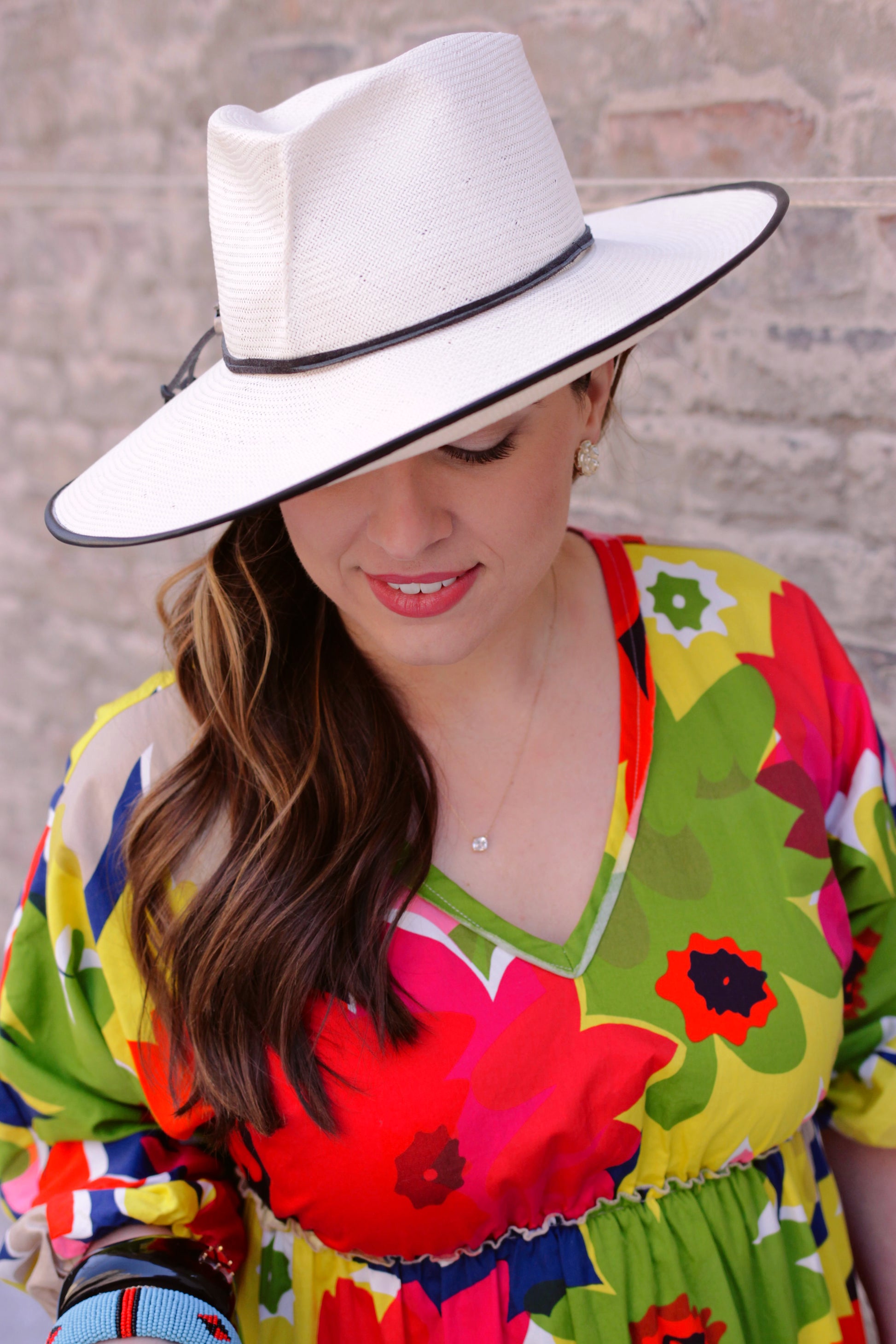 Ivory wide brim travel/beach hat on model. Front view of the hat with a pleat on the crown. 