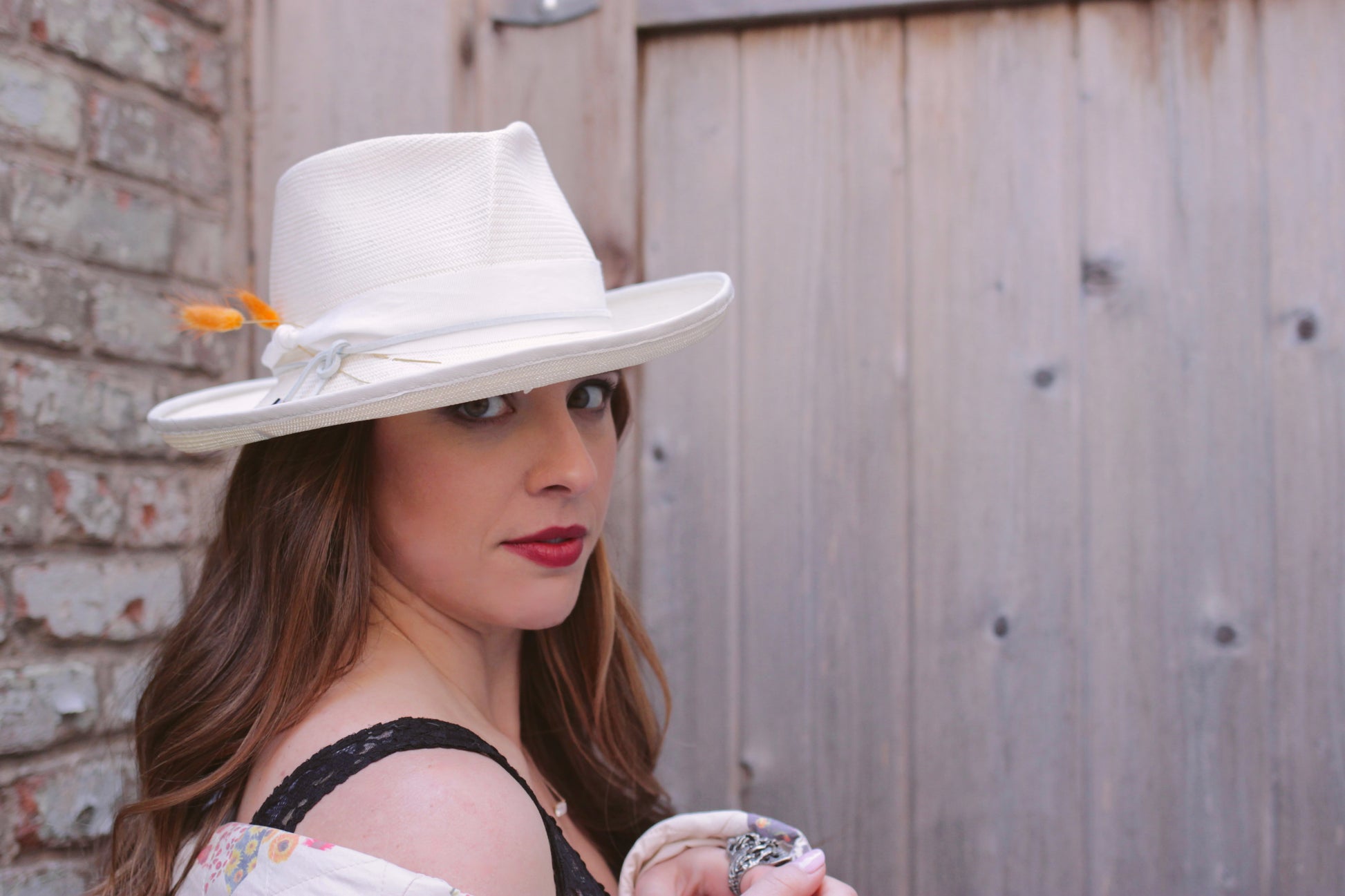 Ivory Straw fedora with 3" brim and a pleated crown. Trimmed with Ivory grosgrain ribbon with suede cord and bunny tails. Brim is piped with matching leather. Front view on model