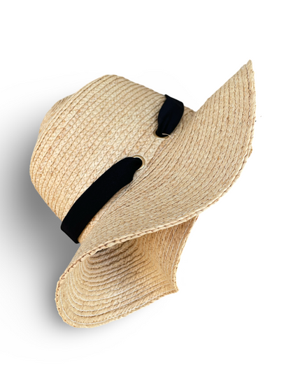 Left side view of Raffia packable travel hat. Black elastic trim laced through two gold grommets. 