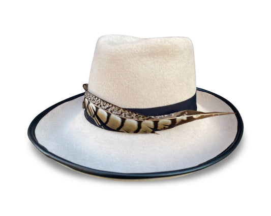 Alabaster Fedora trimmed with black grosgrain and pheasant tail. Brim is piped with black lamb skin